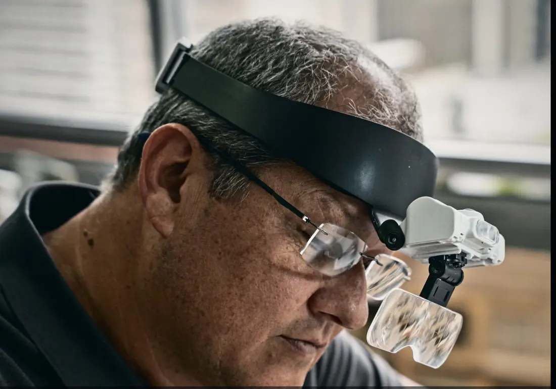 A master cutter wearing magnifying loupes studies a stone
