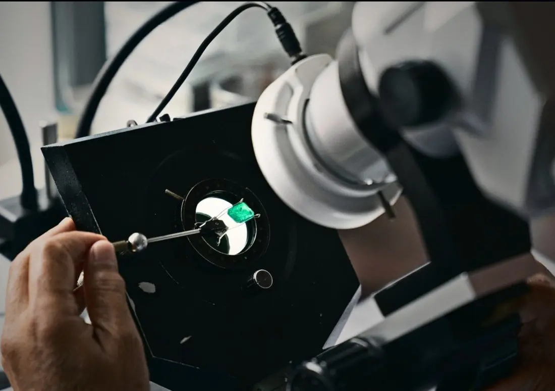 A cut emerald held in the light under the microscope