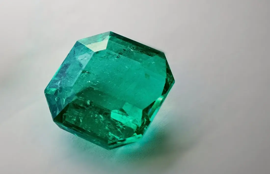 A large emerald-cut Colombian emerald on white paper